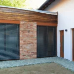 Rodinný dům Počaply – detailní boční pohled na obývací pokoj s plasthliníkovými okny Internorm KF 410 Home Pure a zataženými roletami